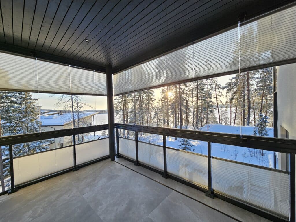 Lasitettu parveke vaaleilla vekkikaihtimilla ja metsänäköalalla